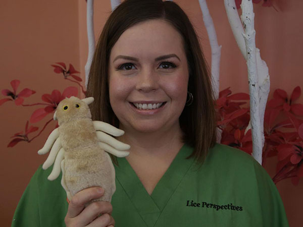 Krystal in green scrubs with a stuffed lice toy.